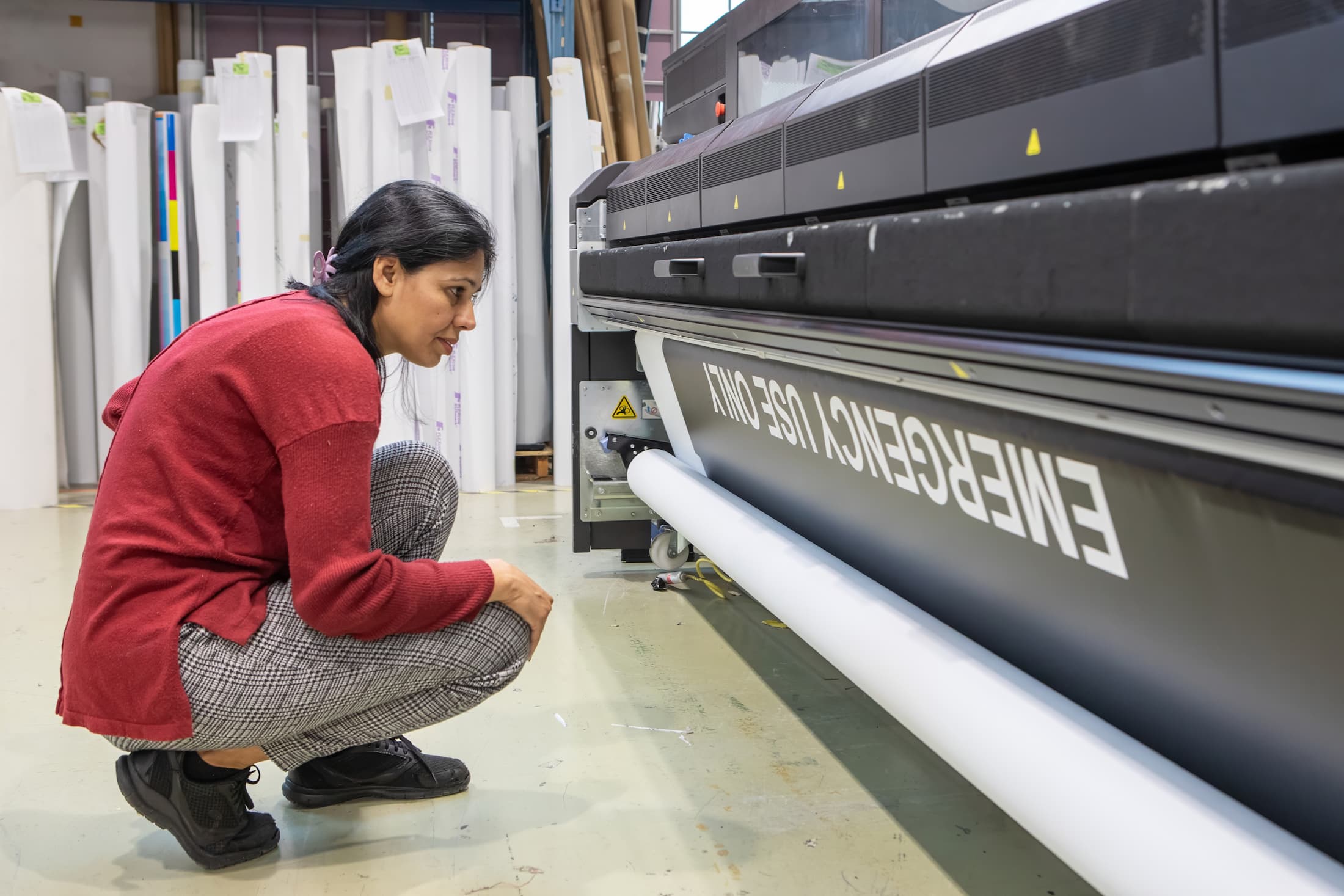 Employee inspecting output on a large-format printer during a quality check.